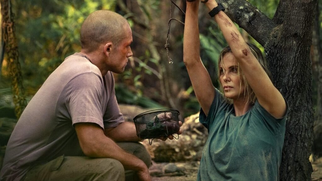 Production still from Apex showing Charlize Theron tied to a tree and Taron Egerton with a shaved head terrorizing her.