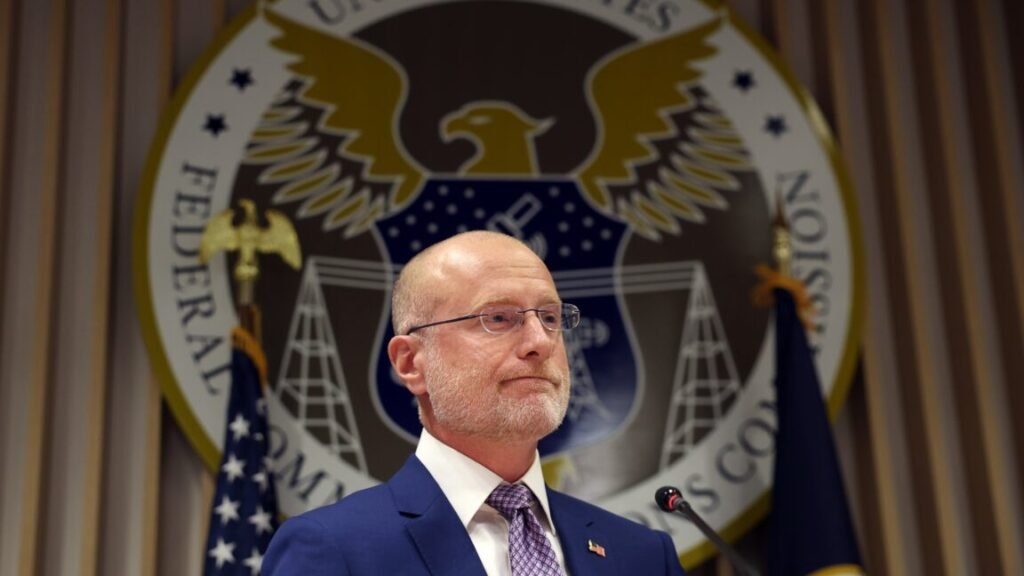 FCC Chairman Brendan Carr at a news conference, standing in front of a flag and an FCC crest.