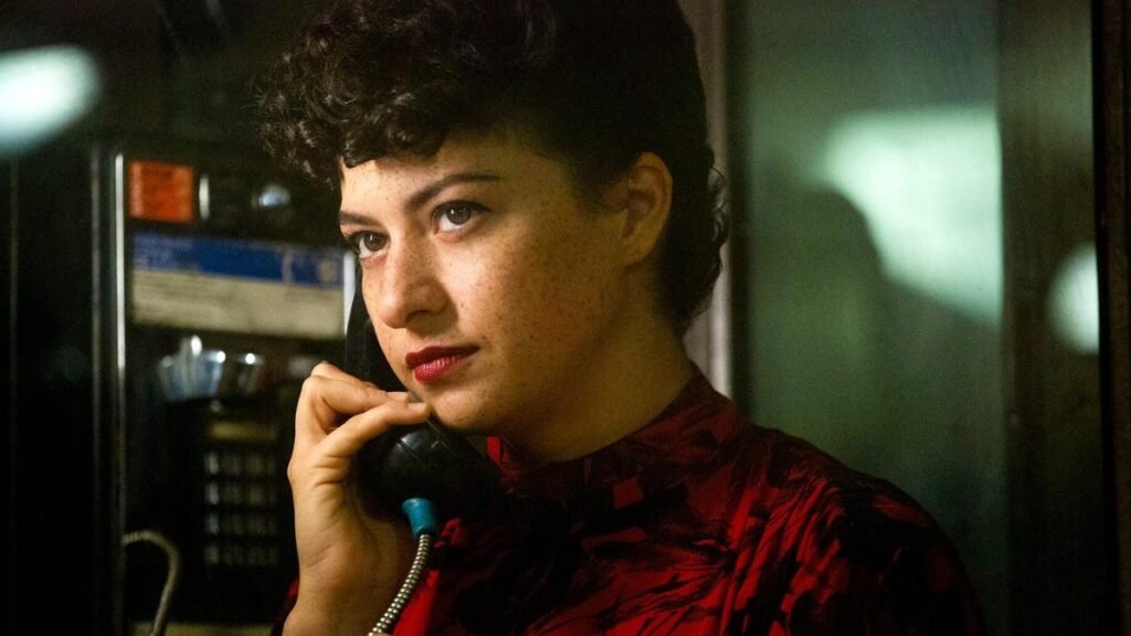 I Just Binged This Underhyped Hipster Comedy on Netflix. Color Me Obsessed Production still from Search Party showing Alia Shawkat wearing a red dress on the phone in a phone booth.