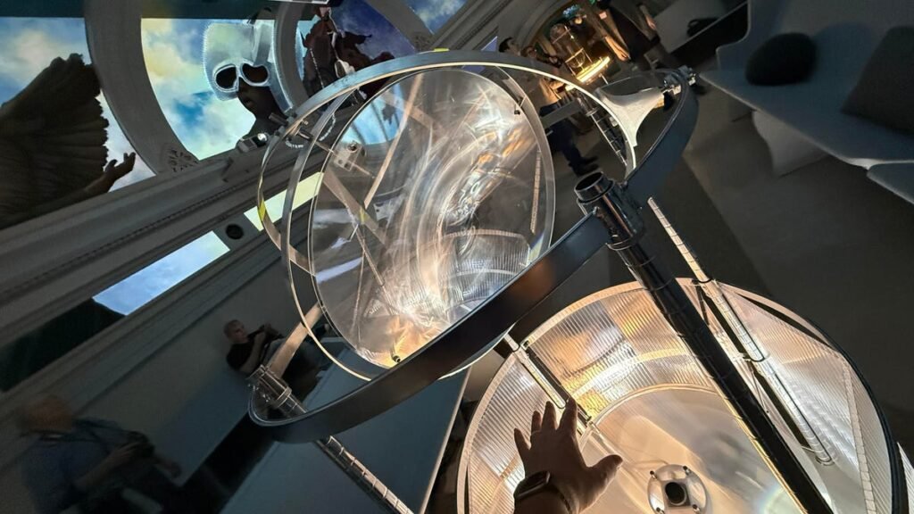 A hand reaching into a hand tracking instrument that glows while mural art hangs in the background