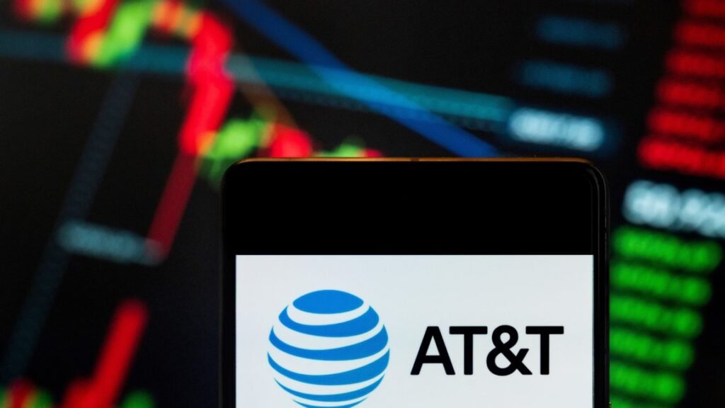 AT&T sues California in attempt to shut off old phone network AT&T logo displayed on a smartphone with a stock exchange index graph in the background.