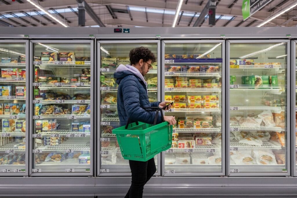 Man standing in front of refrigerator cases at a supermarket.