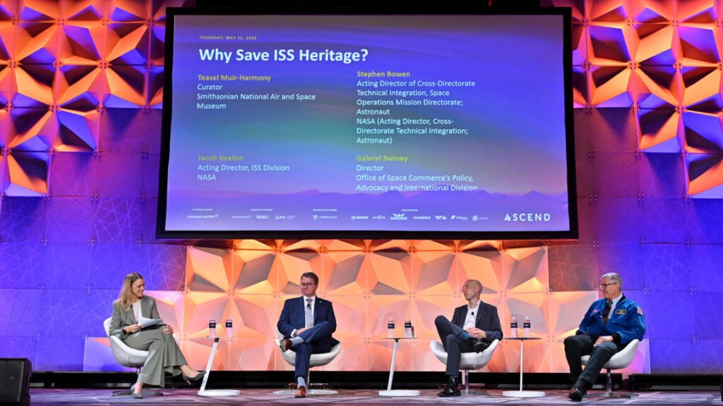 Before it comes down, what should be saved from the International Space Station? Four people sit on a colorfully-lit stage under a large screen displaying their panel title, names and titles.