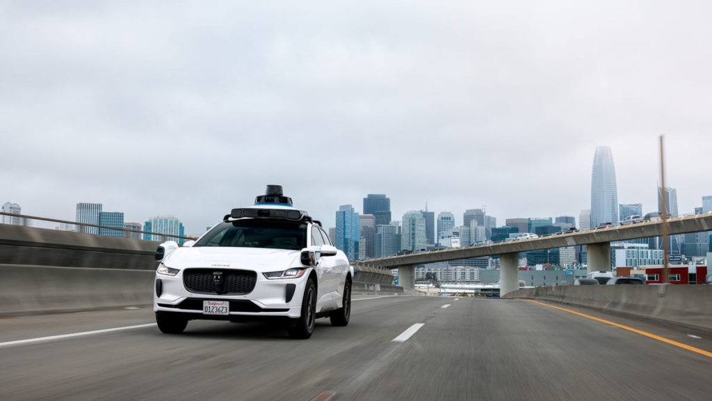 A Waymo-operated Jaguar I-Pace robotaxi drives on a freeway in the San Francisco Bay Area