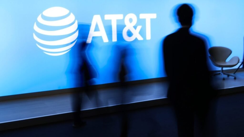 FCC angers small carriers by helping AT&T and Starlink buy EchoStar spectrum People at a conference walk by a large AT&T logo.