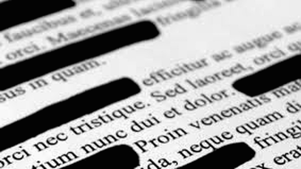 Close-up photograph of a printed document with portions of text redacted by black bars over Latin filler text.