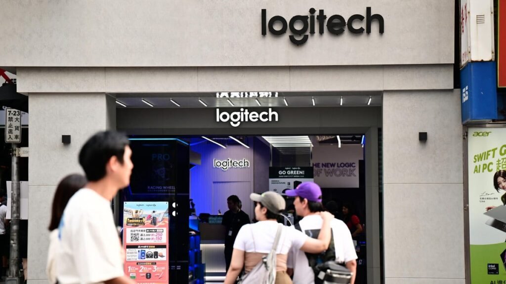 People walk past a Logitech store.