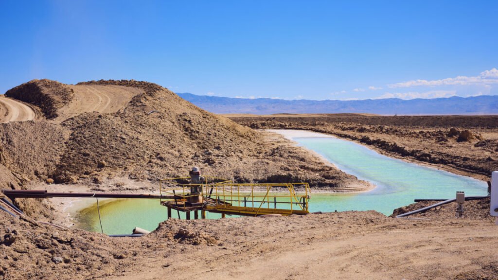Researchers develop a new process to get lithium out of rocks Image of a dry, plant less desert area. In amidst large lumps of soil sit a human-shaped pond of vivid blue water.