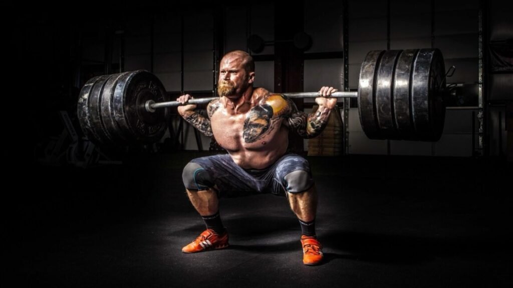 A man performing a squat with a barbell loaded with four weight plates on each end