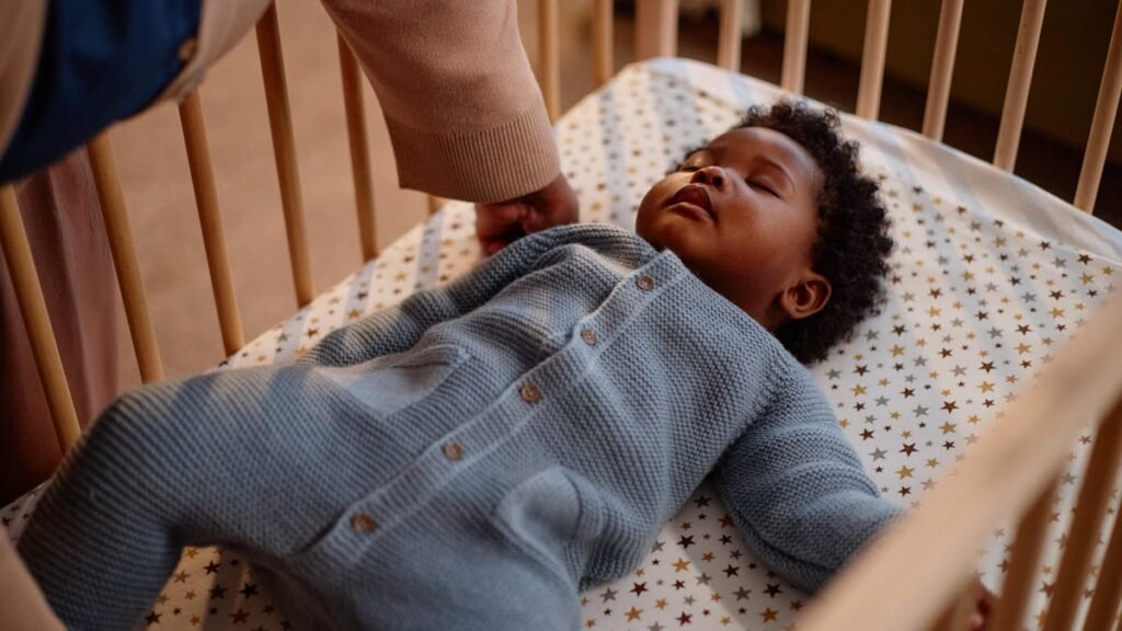 A sleeping Black baby in a crib.