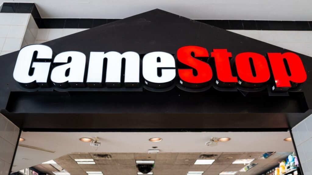 A large GameStop sign hanging above the entrance to a GameStop store inside a mall.