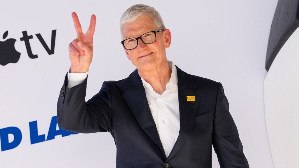 Apple CEO Tim Cook holds up the piece sign.