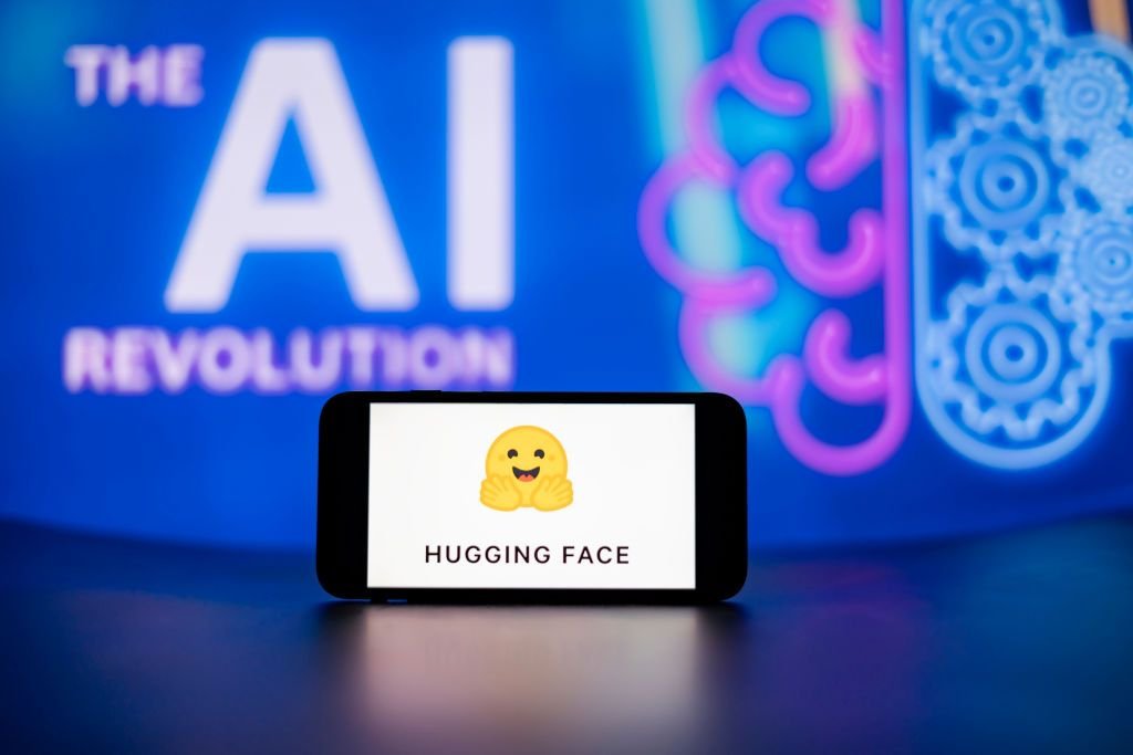 Open-weight AI companies are the Valley’s hottest acquisition targets In this photo illustration, the Hugging Face logo seen displayed on a mobile phone screen with the AI (artificial intelligence) revolution symbol in the background.