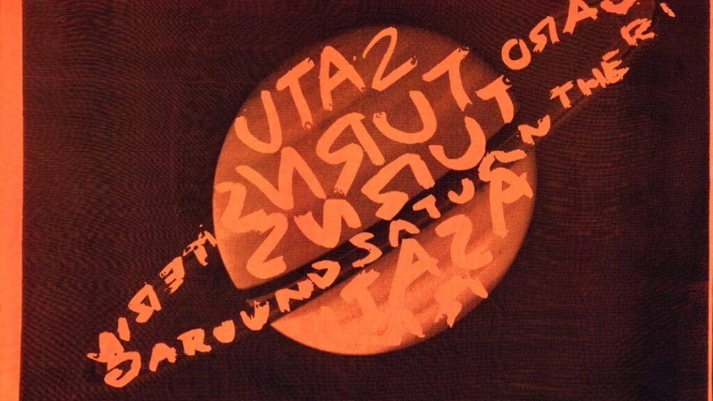 A swath of fabric with a bright orange Saturn covered in black graffiti designed by Stephen Sprouse, 1984-1985.