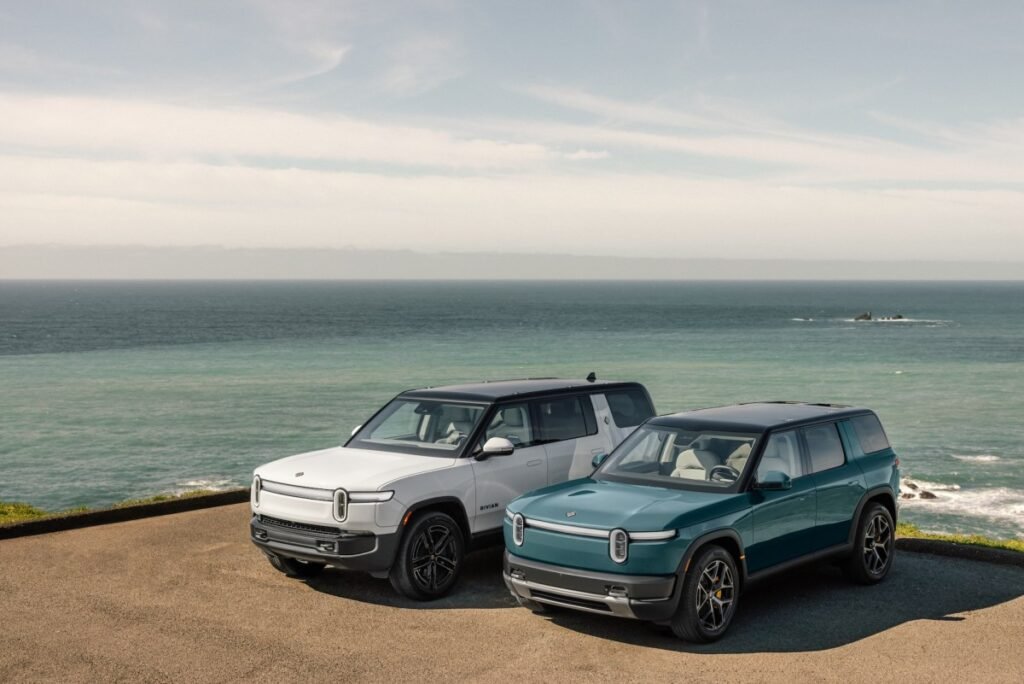 Two Rivian EVs parked by the ocean