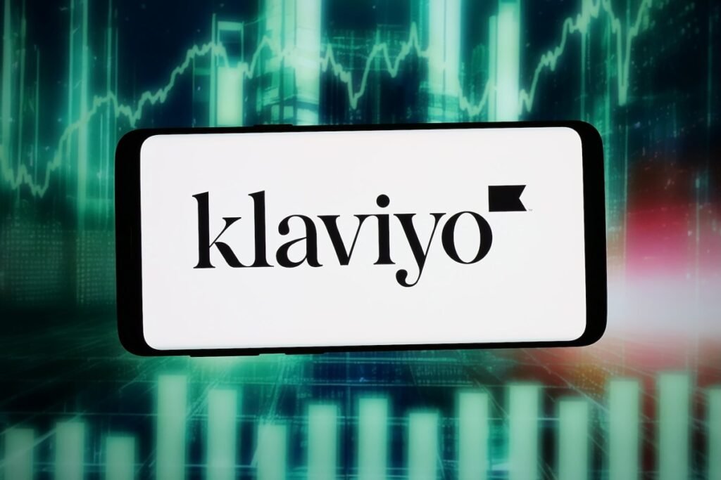 The logo of US marketing automation company Klaviyo Inc. is seen displayed on a smartphone in front of an abstract background on a computer screen.