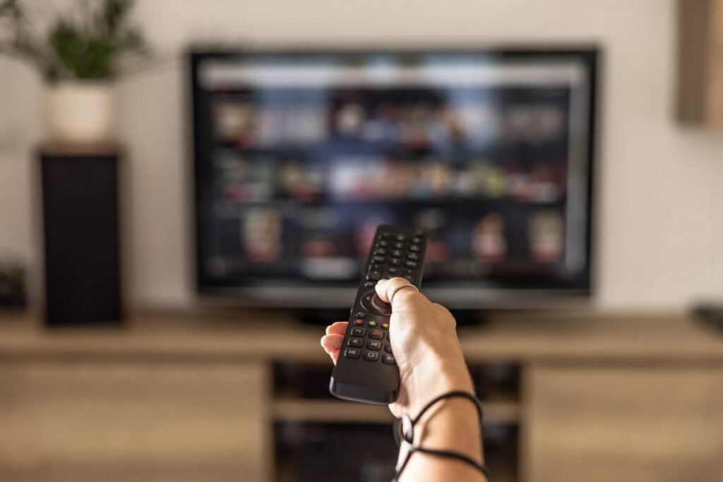 TV Time co-founder launches Bingers to revive the beloved TV tracking app hand holding remote pointed at TV