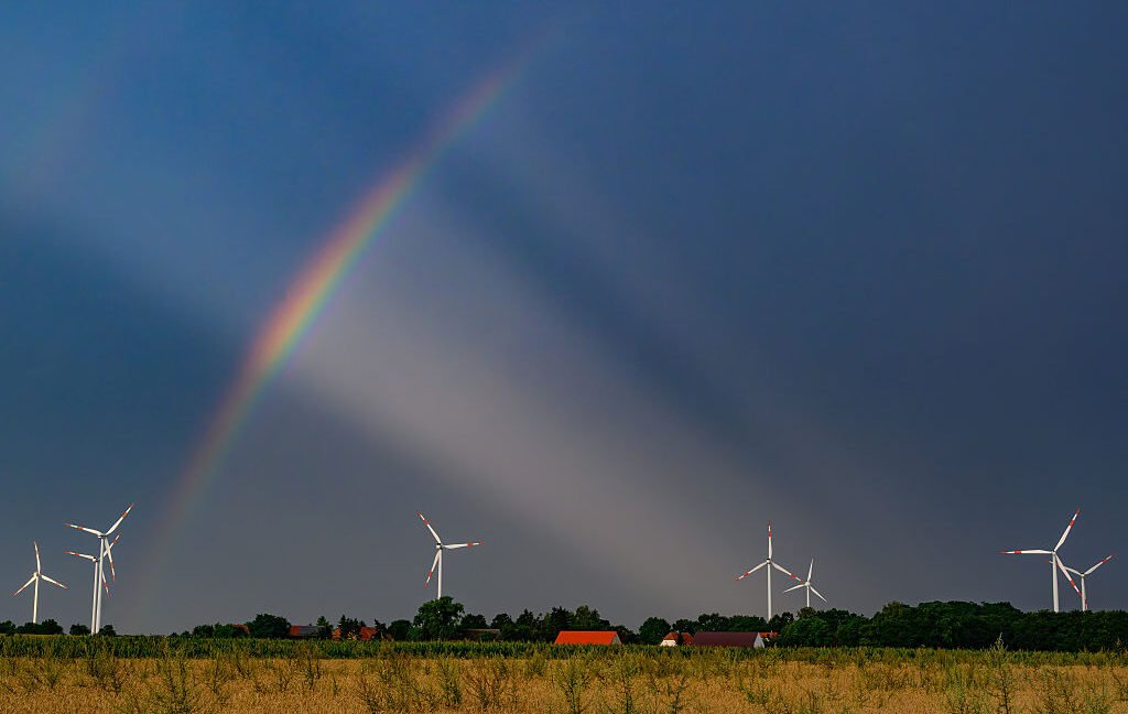 Trump is losing his war on wind power A rainbow and filtered sunlight provide a backdrop for a small wind farm.