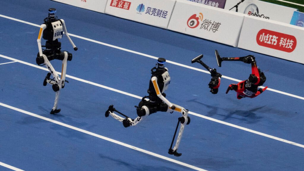 An Honor humanoid robot breaks into pieces as it runs next to two Tian Gong Ultras, center and left, in the second heat of the large robot category of the 100 meter at the 2nd World Robot Games at National Speed Skating Oval on August 25, 2026 in Beijing, China.