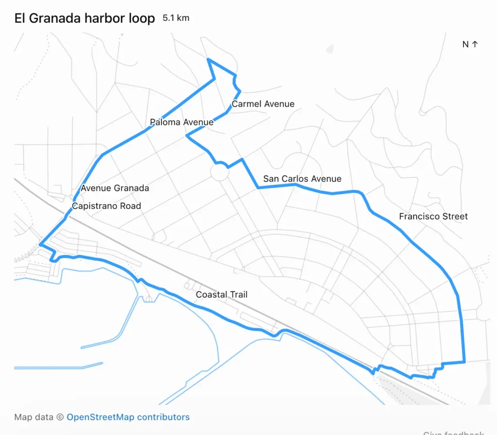 Map screenshot showing a blue route line over a light grey street map. Text: El Granada harbor loop 5.1 km. N ↑ (top right). Street labels along the route: Carmel Avenue, Paloma Avenue, San Carlos Avenue, Avenue Granada, Capistrano Road, Francisco Street, Coastal Trail. The loop runs from the harbor at the bottom left, north along Avenue Granada and Paloma Avenue to a northern point near Carmel Avenue, then east along San Carlos Avenue and south down Francisco Street to the far right, before returning west along the Coastal Trail beside the coastline. Footer: Map data © OpenStreetMap contributors. Give feedback.