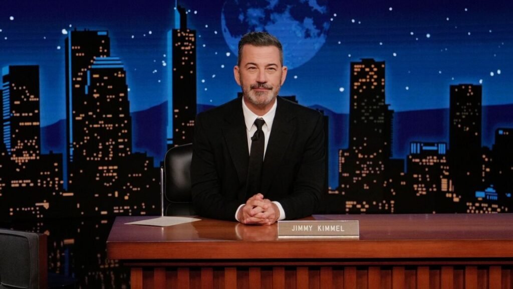 ABC host Jimmy Kimmel sitting at his desk on the set of his show.