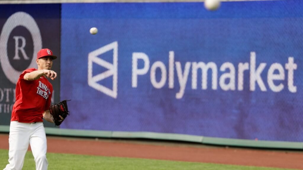 A Major League baseball player throws a ball during warmups, while a large sign advertising Polymarket is seen on the outfield wall.