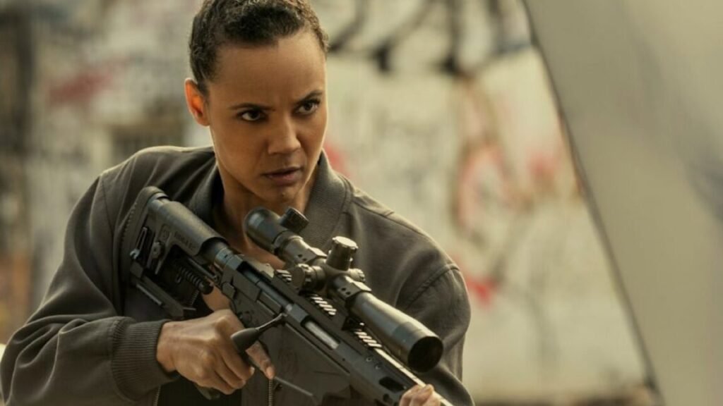 young black woman with hair pulled back in combat gear and holding a high-powered rifle in her hands