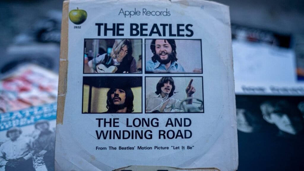 An original Apple Records single sleeve of "The Long and Winding Road," photographed among other Beatles records.
