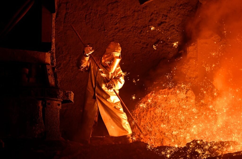 A steelworker takes a sample from a blast furnace.