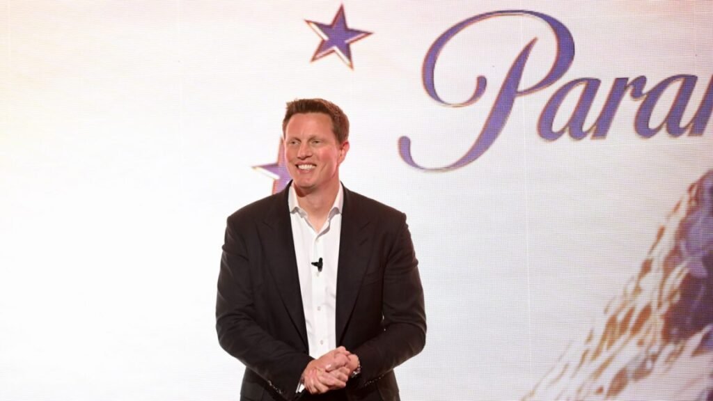 David Ellison stands and smiles in front of a backdrop with a Paramount logo.