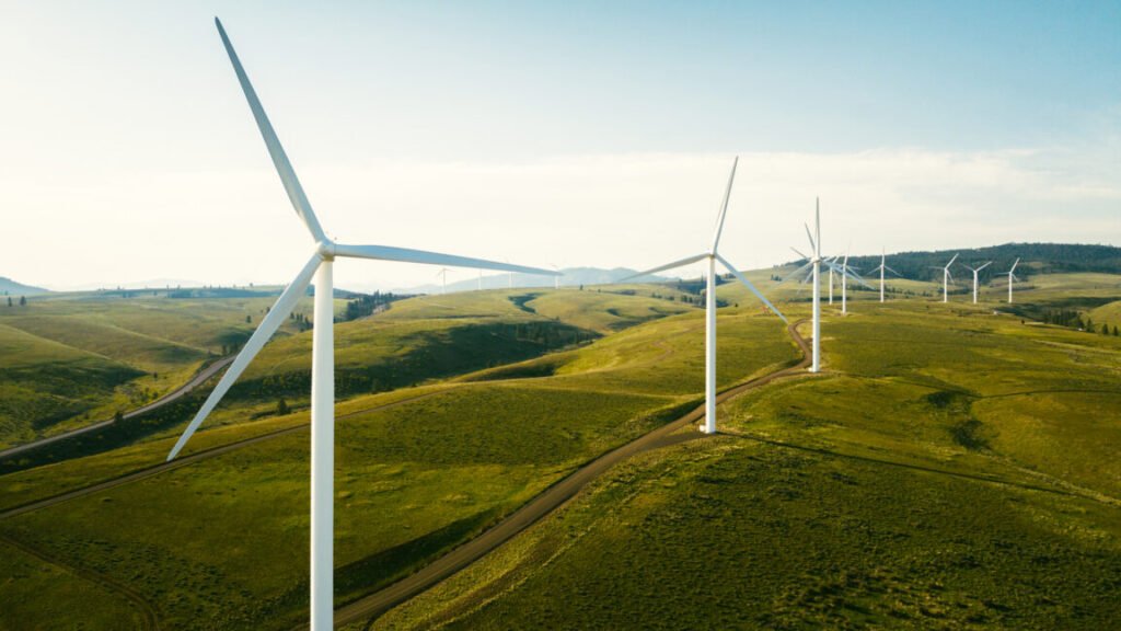 Wind turbines tower above the earth in a rural setting, drawing renewable energy as they spin. Sustainable energy and green technology that considers the environment. Shot in Washington state, USA.